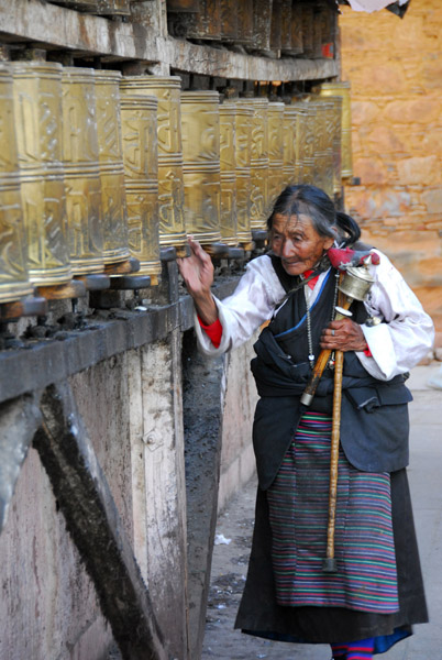Old woman turning the prayer wheels at Mani Lakhang