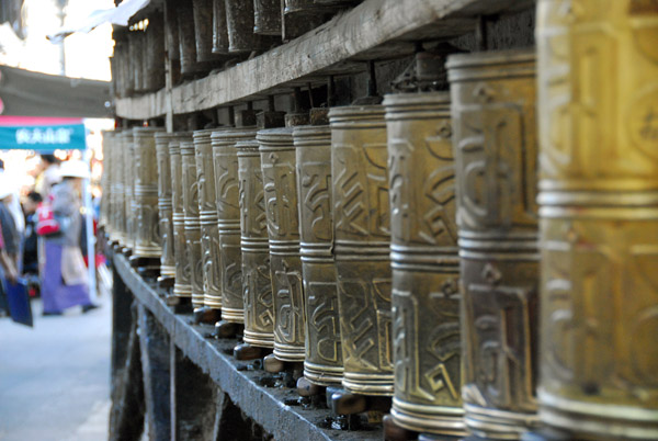 Row of prayer wheels, each with a mantra inscribed on it