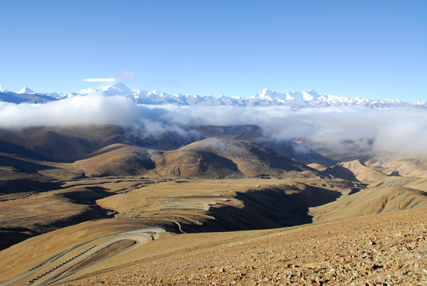 Impressive road down the south side of Pang-la Pass with the Great Himalaya Range above a cloud layer