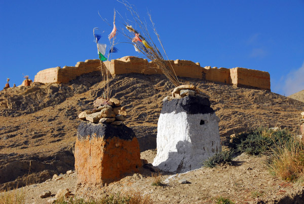 A pair of shrines with prayer flags roadside at the base of the fort