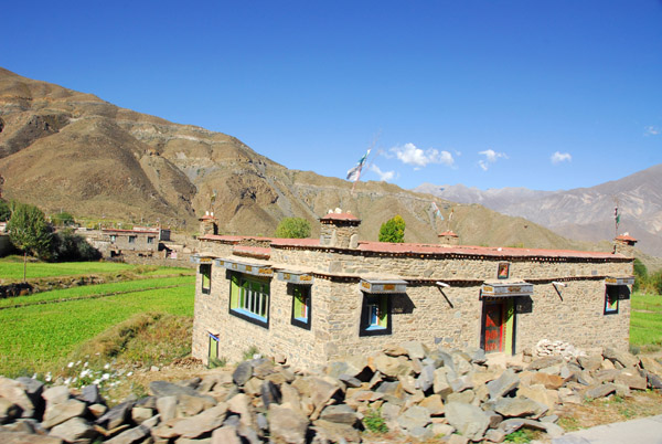 Stone house in front of green fields near Gampa, the village at the base of the Gamba-la pass
