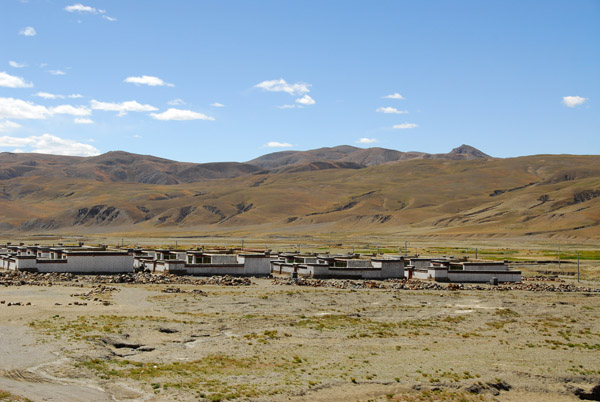 Village of identical Tibetan-style houses on the side of the road