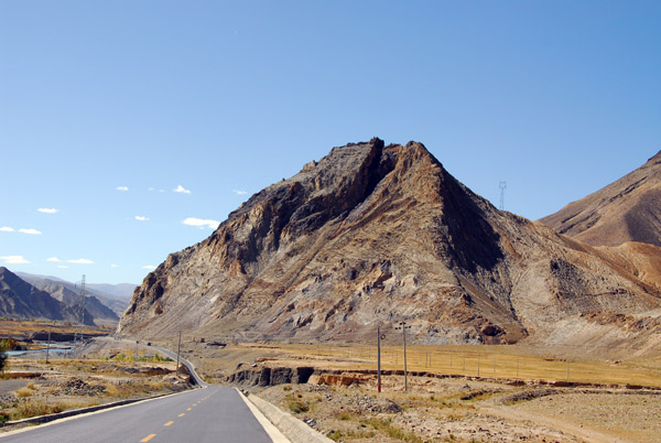 Large hill rising next to the Friendship Highway with ancient ruins at the top