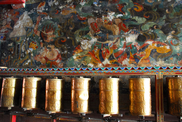 Prayer wheels and murals in need of restoration in the passage leading to the central courtyard