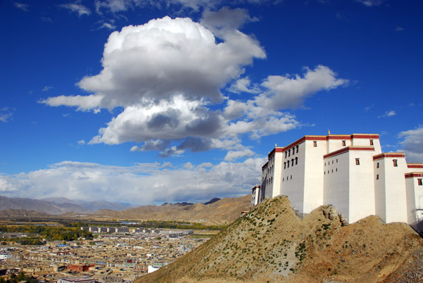 Puffy white clouds in the bright blue sky above Shigatse Dzong