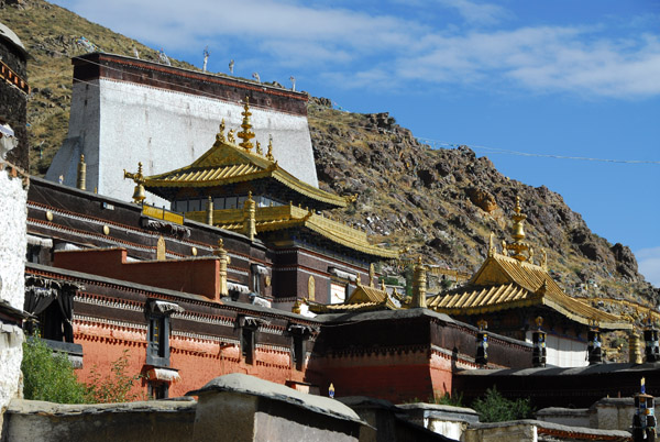 Gilded roofs of Tashilhunpo Monastery with the giant Thangka wall