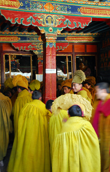 Monks in heavy cloaks filing into the main assembly hall