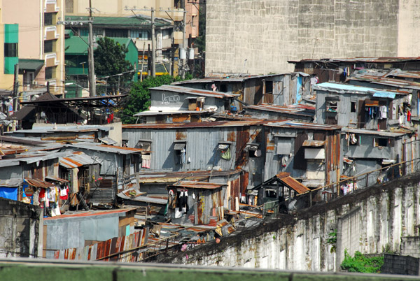 Tin shanties behind a high wall, Recto Avenue, Manila