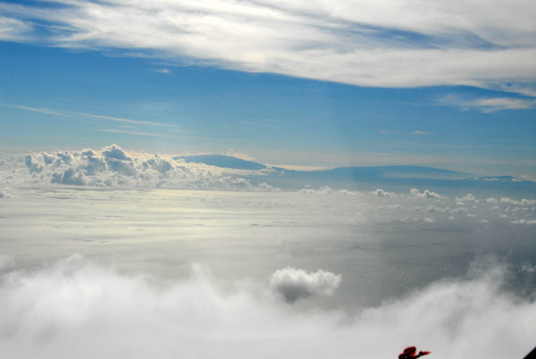 The Big Island of Hawaii reaching up out of the clouds in the distance