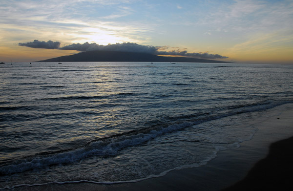 Small waves lapping against the beach at Lahaina with sunset over Lanai