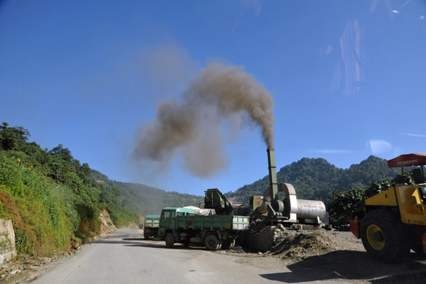 Road construction machinery emiting an ugly plume of smoke into the clean, crisp mountain air, Bhutan