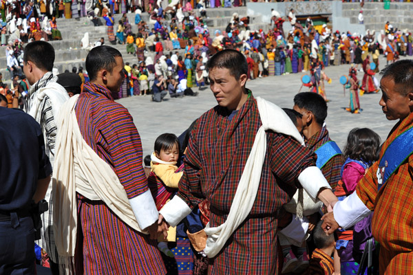 Bhutanese men in white sashes (kabney) keeping order among the crowd