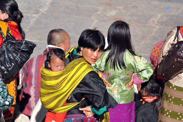 Bhutanese woman with a baby tied to her back with a colorful cloth