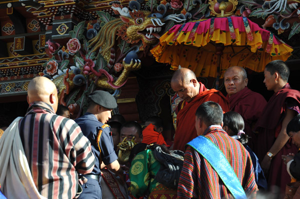 The monk in green touches devotees with the golden hand