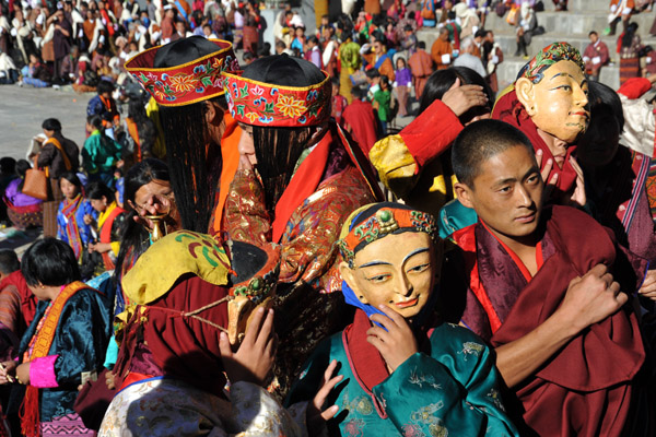 Masked characters and men with hats of long hair, Tsechu Festival