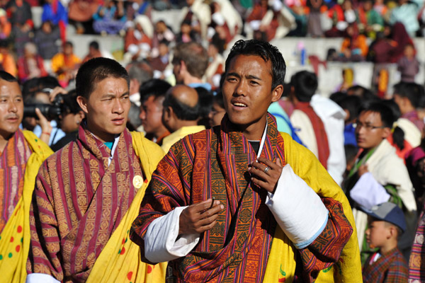 Bhutanese men wearing yellow sashes with green and red dots