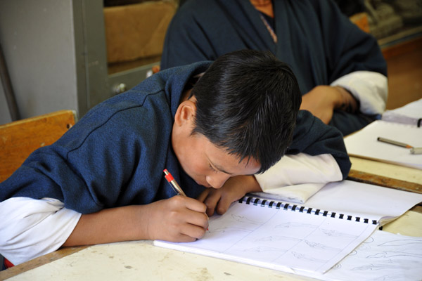 A student concentrating on his drawing