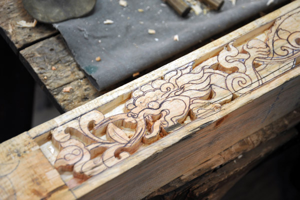 Dragons being carved out of a wooden beam