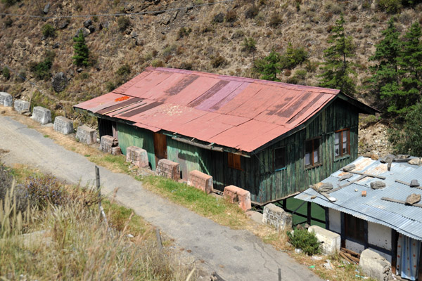 House with a red tin roof built on stilts, Chhuzom