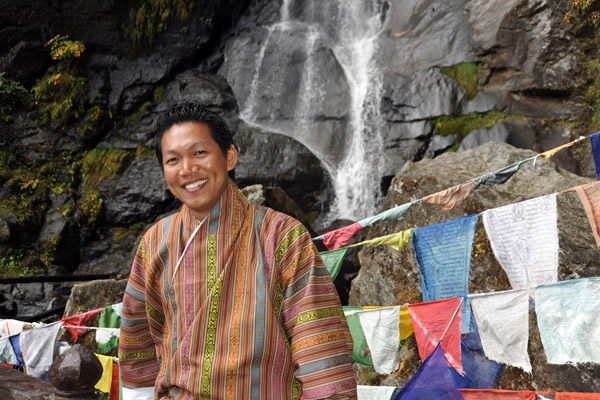 Dennis with prayer flags at the waterfall, Tiger's Nest