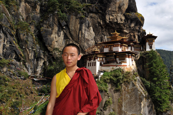 A young Bhutanese monk with Taktshang Goemba, the Tiger's Nest