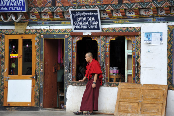 A monk outside Chimi Dem General Shop, Downtown Paro