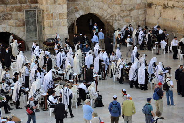 Jewish men in prayer shawls praying at the Western Wall