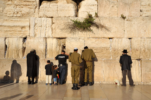 Soldiers, children and a policeman praying at the Western Wall