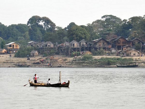 Boat on the Irrawaddy River in front of a stilt village just north of Mandalay