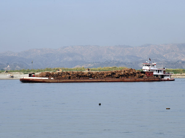 Tugboat pushing a barge loaded with tropical hardwoods cut from the northern forests