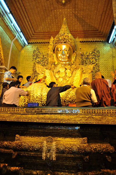 Devotees adding gold leaf to the Mahamuni image