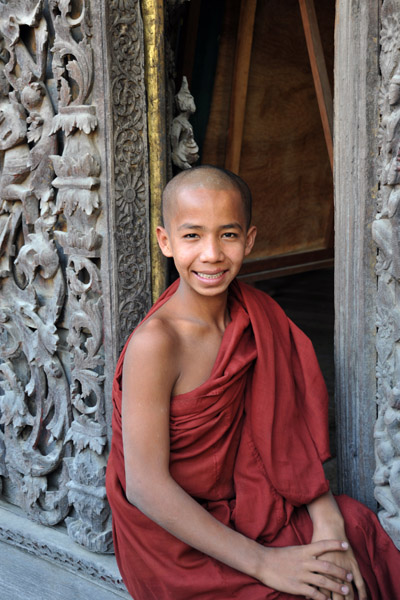 Young monk sitting in a doorway of the Golden Palace Monastery