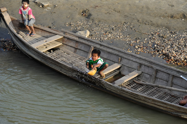 Very young boy bailing out a boat