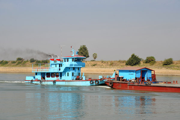 Baby blue tugboat pushing a barget upriver
