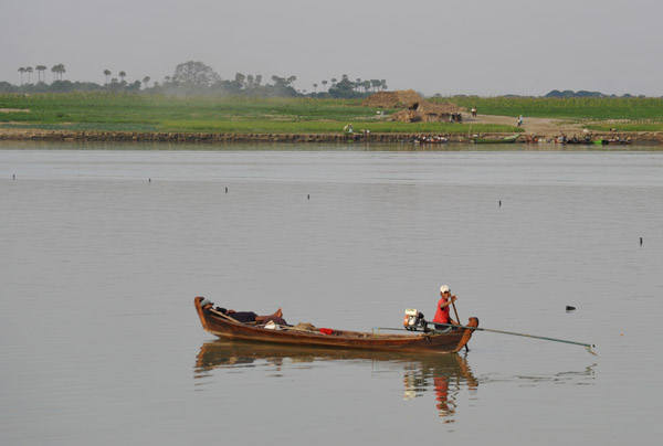Wave from a man in a long-tail boat looking across at the fertile floodplain opposite Bagan
