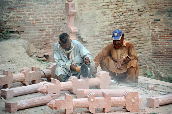 Craftsmen with power tools carving red sandstone for the restoration of a bannister, Lahore Fort