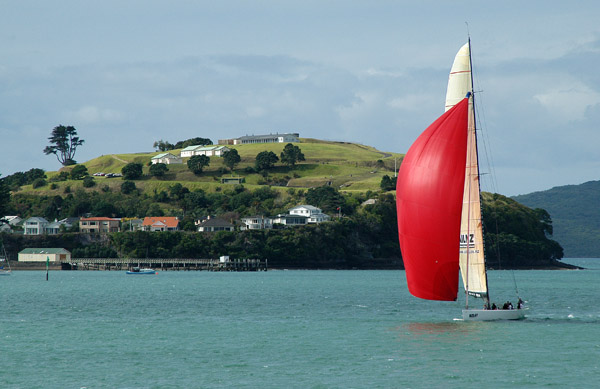 NZL41 flying a red spinnaker in front of Devonports North Head