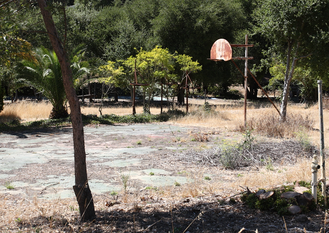 Basketball court and punching bags (minus bags) located next to swimming pools