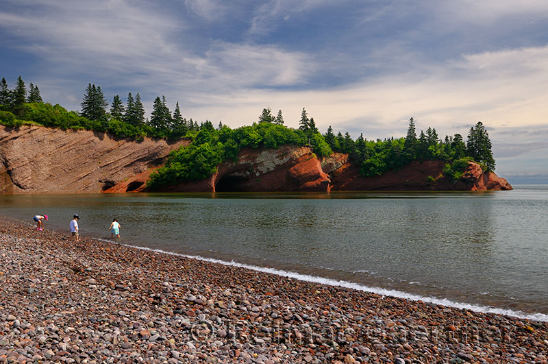 Children playing on pebble beach at sea caves of St Martins New Brunswick at Bay of Fundy high tide