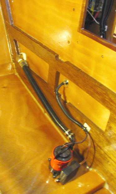 Cuddy bilge pump, forward of the bulkhead.  Aft pump on the other side.  Note chafe protection through bulkhead.