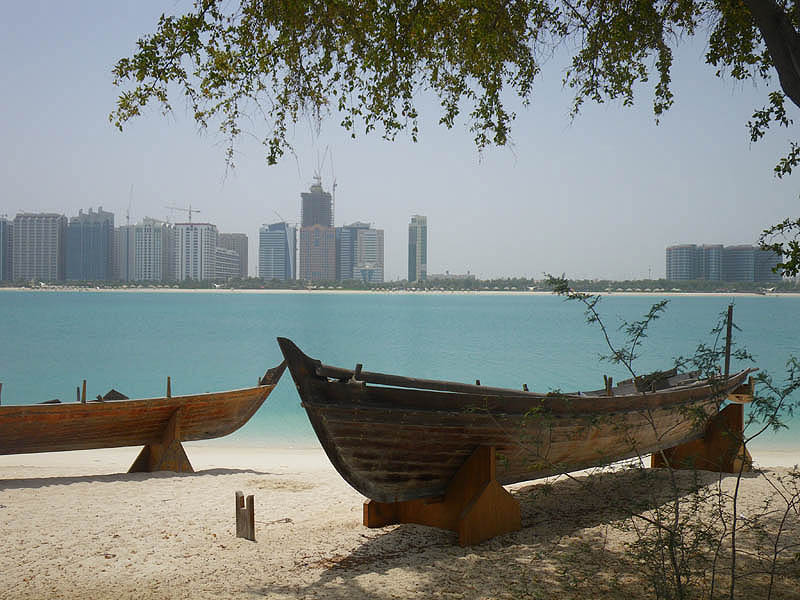 Traditional boats on the beach at the Heritage Village, with city view