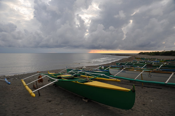 Fishing boats on the beach with clouds and rain blocking sunset