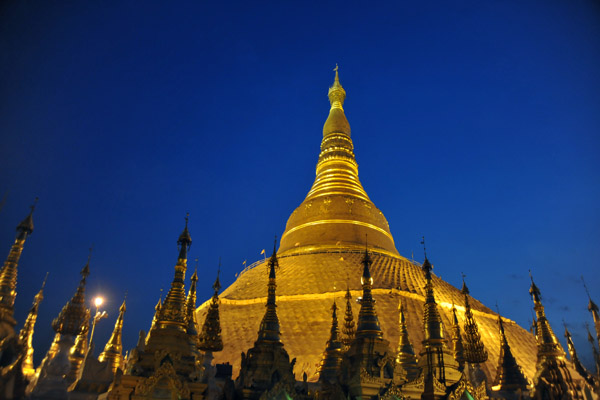 Gold of the main stupa of Shwedagon Paya standing out against a deep blue evening sky