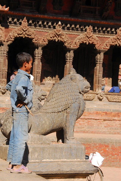 Boy with lion statue in front of Krishna Mandir, Patan
