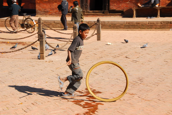 Nepali boy playing with an old bicycle tire, Durbar Square, Patan
