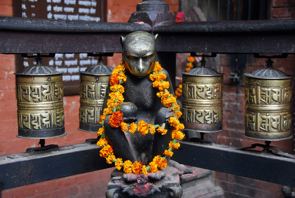 Monkey with flower garland and prayer wheels, Golden Temple (Kwa Bahal) Patan