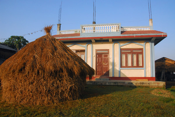 Stack of rice in front of a nicely painted house, Chitrasali