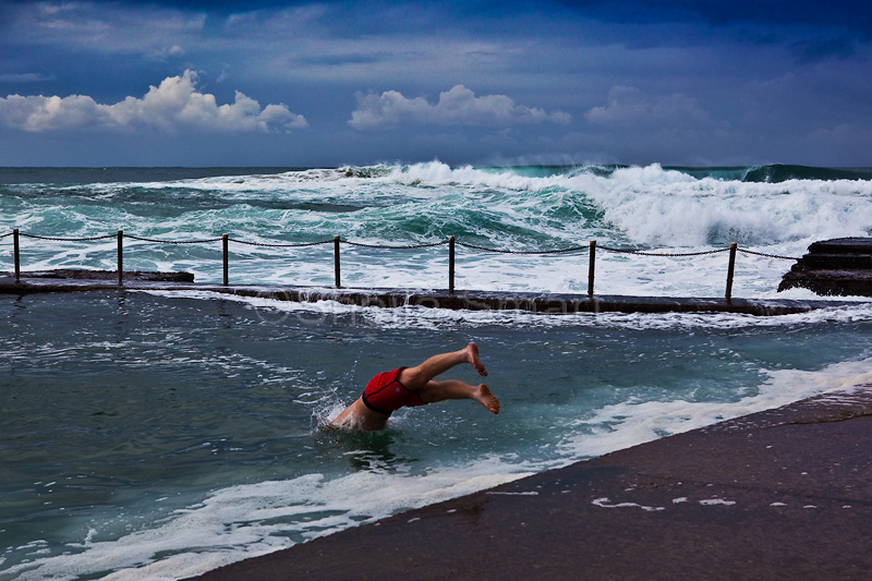 A young man dives into Avalon Rockpool on a winters day