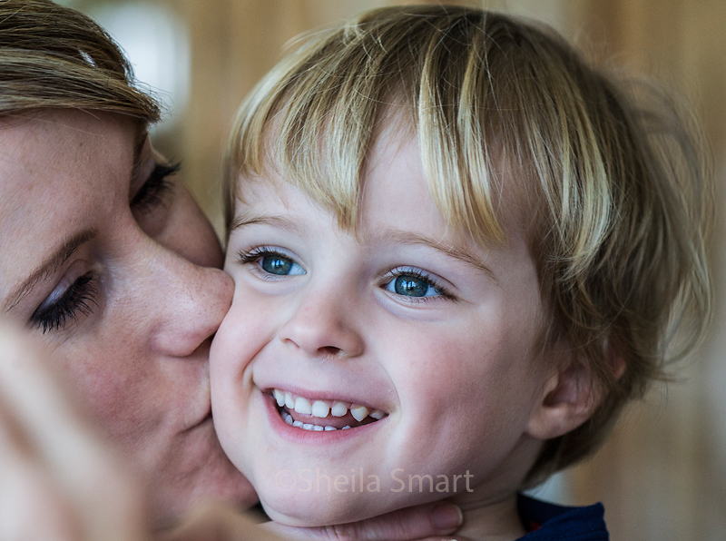 Smiling little boy gets kissed