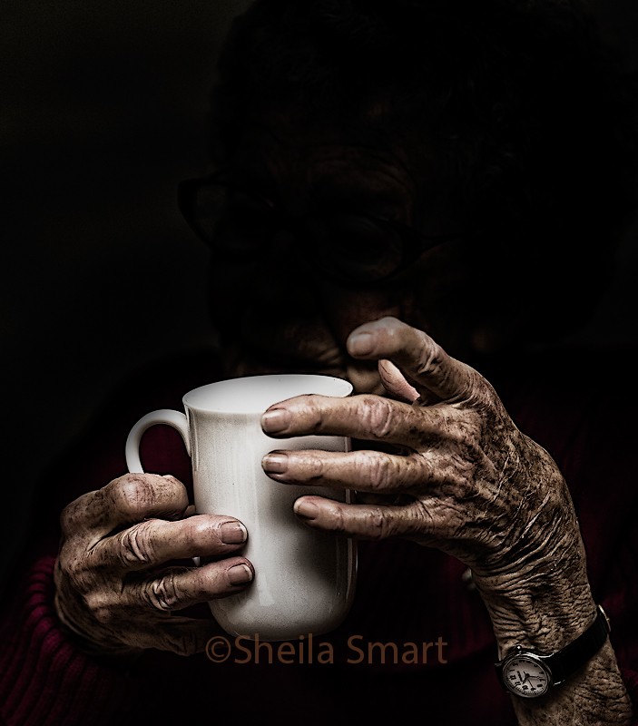 Aged hands hold a mug
